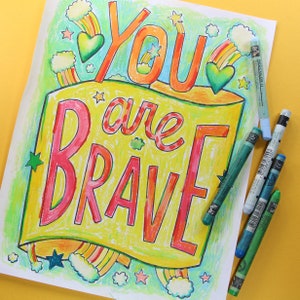 May include: A colourful printable colouring page with the text "You are Brave" in a rainbow banner design. The page features stars, hearts and clouds.
