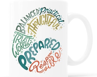 May include: White ceramic mug featuring a design of colourful words such as "Balanced", "Practical", "Thoughtful", "Trustworthy", "Prepared", and "Responsible". The mug has a white handle and the text "KATHY WELLER. WWW.SHOPKATHYWELLER.COM" at the bottom.