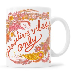 May include: White ceramic coffee mug with a floral design and the text "positive vibes only" in red.