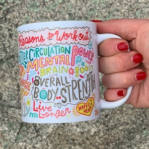 May include: White ceramic mug with colorful hand-lettered text that reads "Reasons to Work Out" including "Better Circulation", "Mental Power", and "Live Longer". The mug is held by a hand with red nail polish.