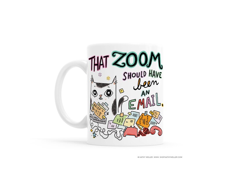 May include: White ceramic mug featuring a cartoon cat surrounded by papers and a phone. The text on the mug reads "That Zoom should have been an email."