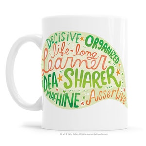 May include: White ceramic mug with a green and orange design. The design features the words "Decisive", "Organized", "Life-long Learner", "Idea Sharer", "Machine", and "Assertive".