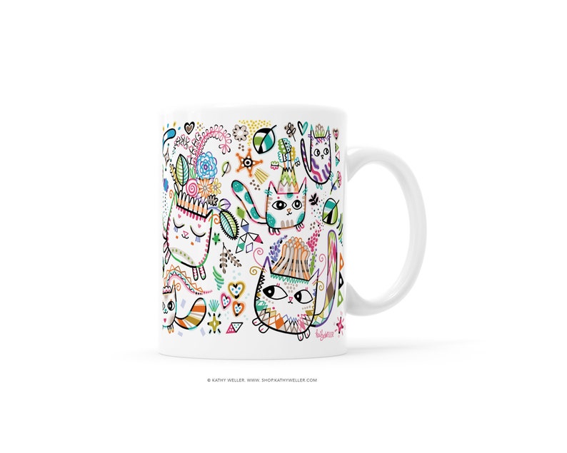 May include: White ceramic mug with a colorful design of cats and flowers. The cats are drawn in a whimsical style with bright colors and patterns. The mug has a handle and is suitable for hot or cold beverages.