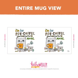 以下が含まれることがあります： 白いセラミック製のマグカップに、コーヒーカップを持った灰色の猫のイラストが描かれています。猫は黄色のシャツを着ており、驚いた表情をしています。マグカップには「I'm in pre-coffee. Don't-mess-with-me mode.」という文字が書かれています。