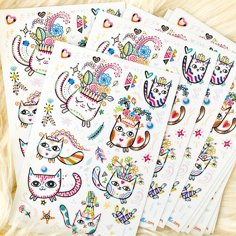 Peut inclure: Un ensemble de six autocollants color&eacute;s repr&eacute;sentant des chats fantaisistes avec des couronnes de fleurs et d'autres &eacute;l&eacute;ments d&eacute;coratifs. Les autocollants sont imprim&eacute;s sur du papier blanc et ont une finition brillante.
