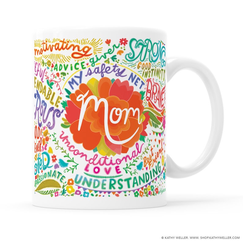 May include: White ceramic mug with a colorful design featuring the word "Mom" surrounded by words describing positive qualities, such as "strong", "brave", "love", and "understanding".