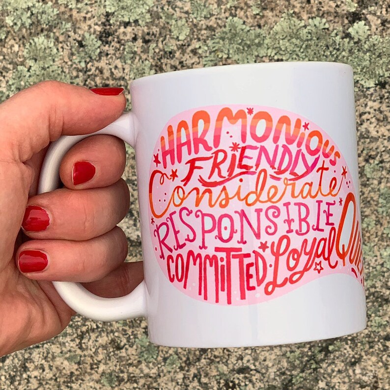 May include: White ceramic mug with a pink and orange graphic that says "Harmonious, Friendly, Considerate, Responsible, Committed, Loyal, Queen".