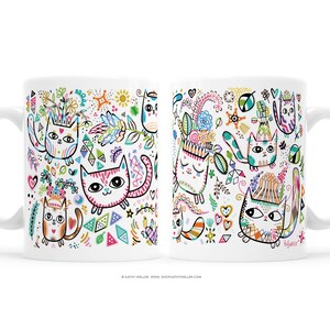 May include: White ceramic mug with a colorful design of cats with flowers, geometric shapes, and stars. The mug has a handle on the left side.