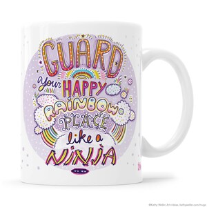 May include: White ceramic mug with a purple background and colorful text that reads "Guard your happy rainbow place like a ninja".