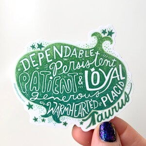 Puede incluir: Pegatina verde y blanca con el texto "Dependable, Persistent, Patient & Loyal, Generous, Warmhearted, Placid, Taurus" en una fuente estilizada. La pegatina tiene un dise&ntilde;o de estrellas alrededor de los bordes.