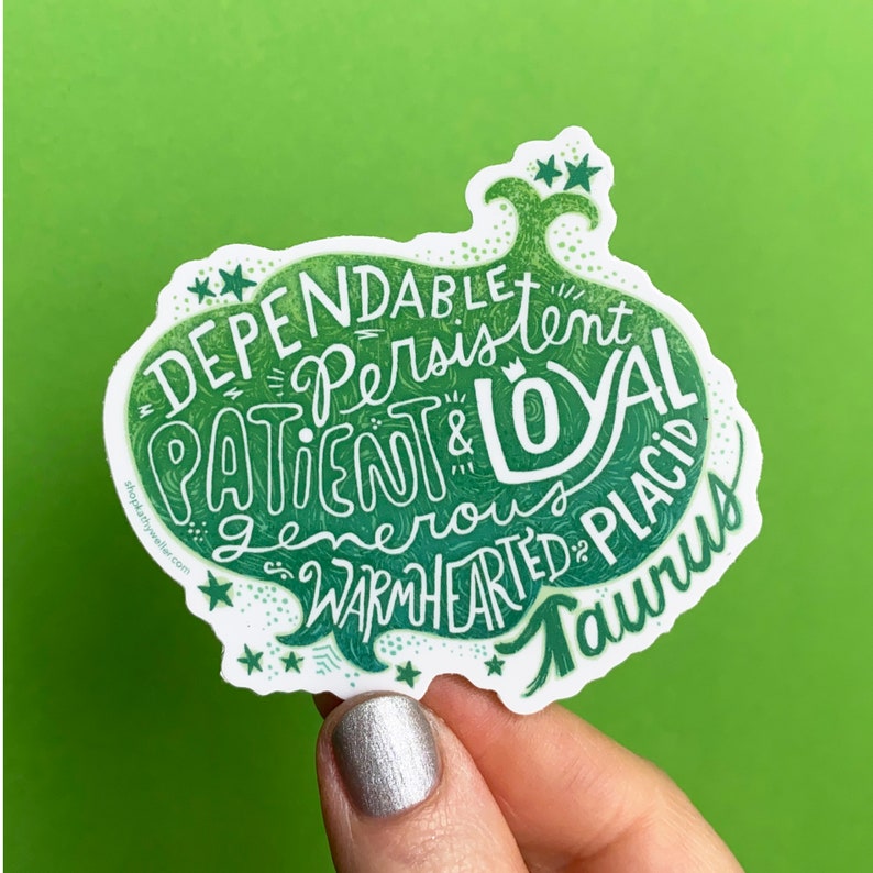 Puede incluir: Pegatina verde y blanca con el texto "Dependable, Persistent, Patient & Loyal, Generous, Warmhearted, Placid, Taurus" en una fuente estilizada. La pegatina tiene la forma de una cabeza de toro.