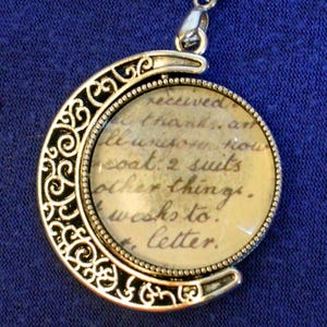 Collar de cabujón con letras manuscritas antiguas en un cordón gris de 45 cm con una cadena extensora reversible de 5 cm.