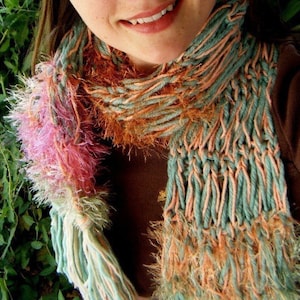May include: A long, multi-colored scarf with a fuzzy texture. The scarf is made of a blend of pink, orange, and green yarn.