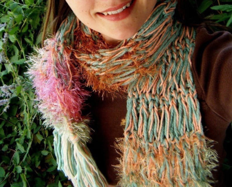 May include: A long, multi-colored scarf with a fuzzy texture. The scarf is made of a blend of pink, orange, and green yarn.
