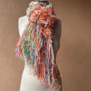May include: A colorful scarf with a fringe design. The scarf is made of a soft, textured yarn and is available in a variety of colors.