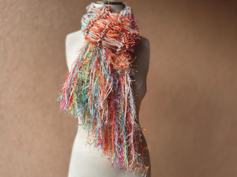 May include: A colorful scarf with a fringe design. The scarf is made of a soft, textured yarn and is available in a variety of colors.