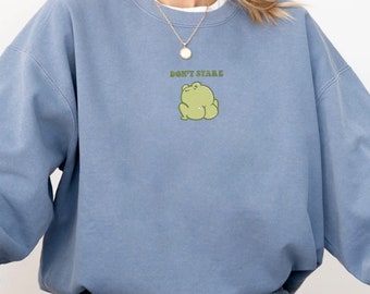 May include: A light blue sweatshirt with a green frog graphic and the text "Don't Stare".