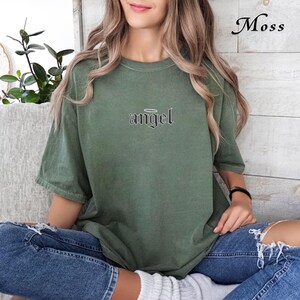 May include: A green oversized t-shirt with a black graphic that says "angel" with a halo above the word.