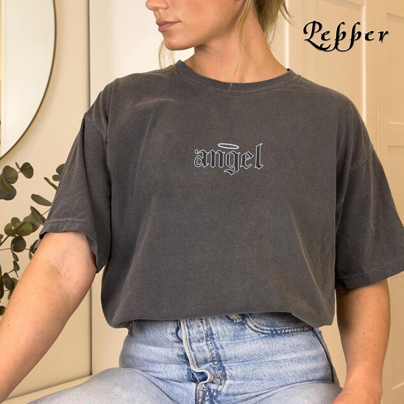 May include: A dark gray t-shirt with the word "angel" in white lettering with a halo above it.