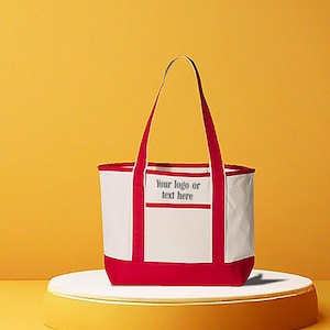May include: A white tote bag with red accents, including the base, handles, and trim. The bag features a rectangular pocket with the text "Your logo or text here." The bag is displayed on a white platform against a yellow background.