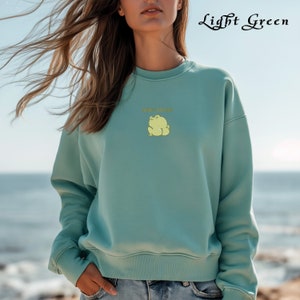 May include: A light green sweatshirt with a frog graphic and the text "Don't Stare" in yellow.