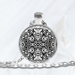 May include: A silver chain necklace with a round pendant featuring a black and white geometric design.