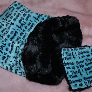 May include: A blue fabric pouch with a black fuzzy lining. The pouch is decorated with the text "I solemnly swear that I am up to no good" repeated multiple times. The text is in a black font and is surrounded by lightning bolts.