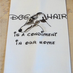 May include: White kitchen towel with black embroidery of a dog's head and the text "DOG HAIR IS A CONDIMENT IN OUR HOME".
