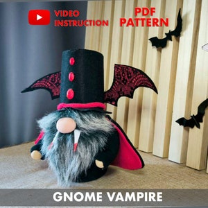 May include: A black and red gnome vampire with a black hat and a red cape. The gnome has a white nose and fangs. The gnome is standing on a wooden surface. "Gnome Vampire" is written below the gnome.