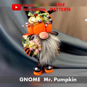 Puede incluir: Un gnomo de calabaza naranja hecho a mano con un atuendo a rayas negro y naranja, una barba gris y un sombrero de calabaza con flores. El gnomo sostiene un ramo de flores. La imagen incluye el texto "VIDEO INSTRUCTION" y "PDF PATTERN".