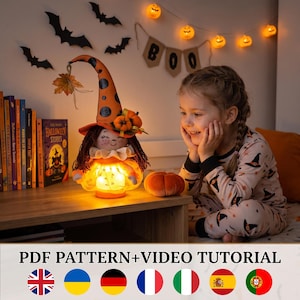 May include: A fabric witch doll with a tall orange hat featuring black polka dots, brown yarn hair, and a ruffled collar. The doll has an illuminated skirt with a warm glow. The text PDF PATTERN+VIDEO TUTORIAL is displayed at the bottom.