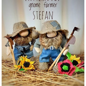May include: Two gnome farmer dolls with brown beards, wearing blue jeans, plaid shirts, and straw hats. They are holding gardening tools and are sitting on a bed of straw with sunflowers and red poppies.