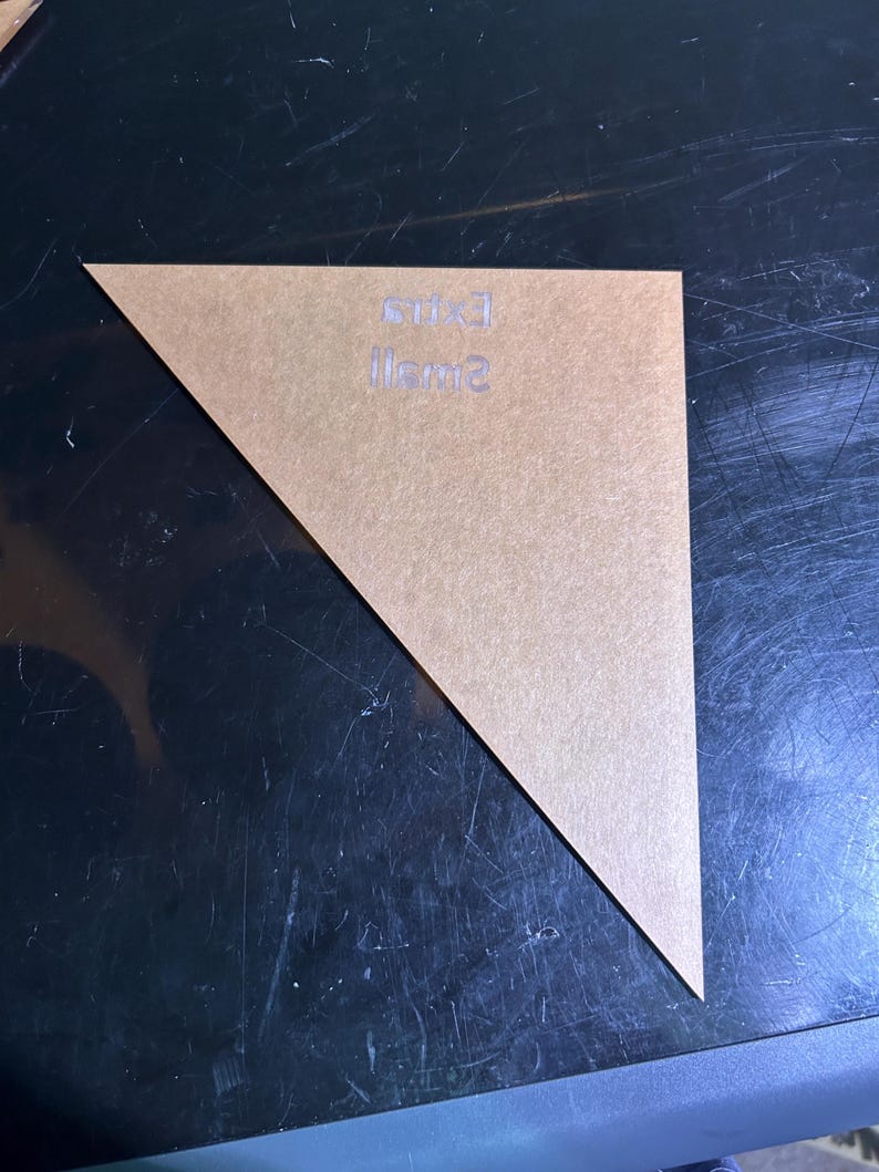 K&ouml;nnte beinhalten: Ein klares, dreieckiges Acrylteil mit den Worten "small" und "exit" auf der Oberfl&auml;che. Das Teil hat eine hellbraune Farbe und liegt auf einer dunklen, reflektierenden Oberfl&auml;che.