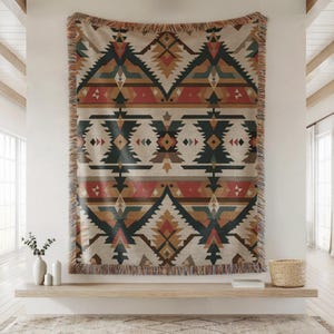 May include: A woven tapestry with a geometric pattern in shades of beige, black, red, and brown. The tapestry has a fringed edge and is displayed on a wall. The design features repeating diamond and triangle shapes, creating a Southwestern or Native American aesthetic.