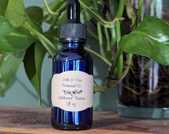 Puede incluir: Una botella de vidrio azul con un gotero y una etiqueta de papel marrón que dice "34th & Vine Botanical Co. Goldenrod Tincture 1 fl. oz."
