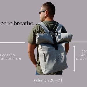 K&ouml;nnte beinhalten: Ein grauer Rucksack mit Rollverschluss und schwarzem Trageriemen. Der Rucksack hat ein Logo mit dem Buchstaben "B" und dem Wort "BRATE". Der Text "50% MEHR STAURAUM" und "Volumen: 20-401" ist auf dem Bild zu sehen. Der Text "STILVOLLES WILDLEDERDESIGN" ist ebenfalls auf dem Bild zu sehen.