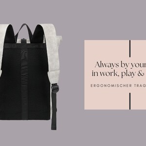 K&ouml;nnte beinhalten: Ein grauer und schwarzer Rucksack mit einem Mesh-R&uuml;ckenpanel und verstellbaren Tr&auml;gern. Der Rucksack hat den Text "Always by your side, in work, play & health" und "ERGONOMISCHER TRAGEKOMFORT" auf einem rosa Hintergrund.