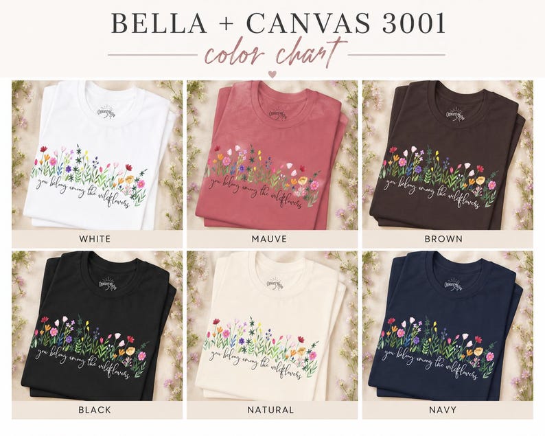 以下が含まれることがあります： 白、モーヴ、茶色、黒、ナチュラル、ネイビーの6色展開のBella + Canvas 3001 Tシャツのカラーチャート。各シャツには、テキスト「you belong among the wildflowers」と花の模様が施されています。