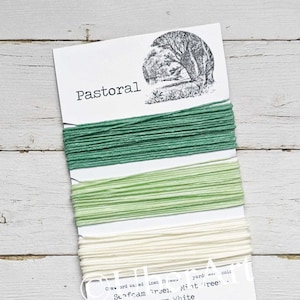 May include: Three spools of twine in shades of green and white. The twine is labeled "Pastoral" and includes the colors "Seafoam Green", "Mint Green", and "Warm White".