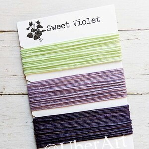 May include: Three spools of embroidery floss in mint, lavender, and plum colors. Each spool contains five yards of floss. The card reads "Sweet Violet" and "UberArt" with the website address www.Etsy.com/shop/UberArt.