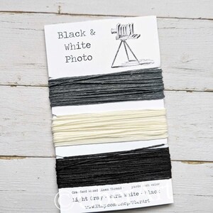 May include: A card labeled "Black & White Photo" with three bundles of thread in light gray, warm white, and black. The card also features a drawing of a vintage camera and the text "Cra ford waxed linen Thread".