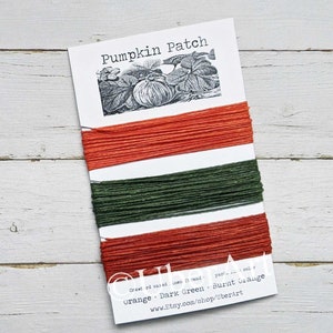May include: Three spools of waxed cotton thread in orange, dark green, and burnt orange colors. The spools are labeled "Pumpkin Patch" and "Orange - Dark Green - Burnt Orange".