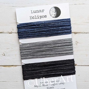 May include: A card with three spools of thread in shades of blue, gray, and black. The card is labeled "Lunar Eclipse" with the colors "Royal Blue", "light gray", and "Black" listed below. The Etsy shop name "UberArt" is also visible.