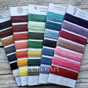 May include: A color chart of waxed linen cord in various colors, including neutrals, greens, blues, pinks, and reds. The chart is labeled with the color names and the brand name "UberArt".