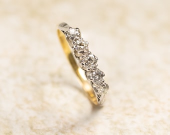 Puede incluir: Una delicada banda de oro con una fila de diamantes brillantes engastados en un diseño curvo.