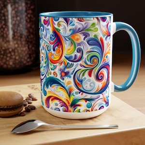 May include: A large white ceramic mug with a blue rim and handle. The mug features a colorful, swirling floral pattern in shades of blue, green, yellow, orange, red, and purple.