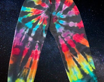 May include: Black sweatpants with a colorful tie-dye pattern in shades of pink, blue, green, yellow, and orange. The pattern is a spiral design.