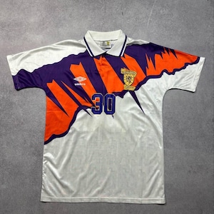 May include: White soccer jersey with purple and orange accents. Features the number 30 in blue, a collar, and the Umbro logo. The jersey has a Scottish Football Association emblem.