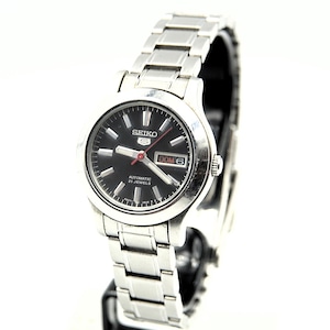 May include: A silver Seiko automatic wristwatch with a black face. The watch has silver hour markers, hands, and a day-date display. The watch strap is made of silver metal links.