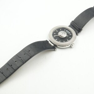 Puede incluir: Un reloj de pulsera con correa negra texturizada y caja redonda plateada. La esfera negra presenta un emblema central de cabeza de le&oacute;n plateado, manecillas plateadas y el texto Versus Versace. El bisel tiene una textura finamente moleteada.